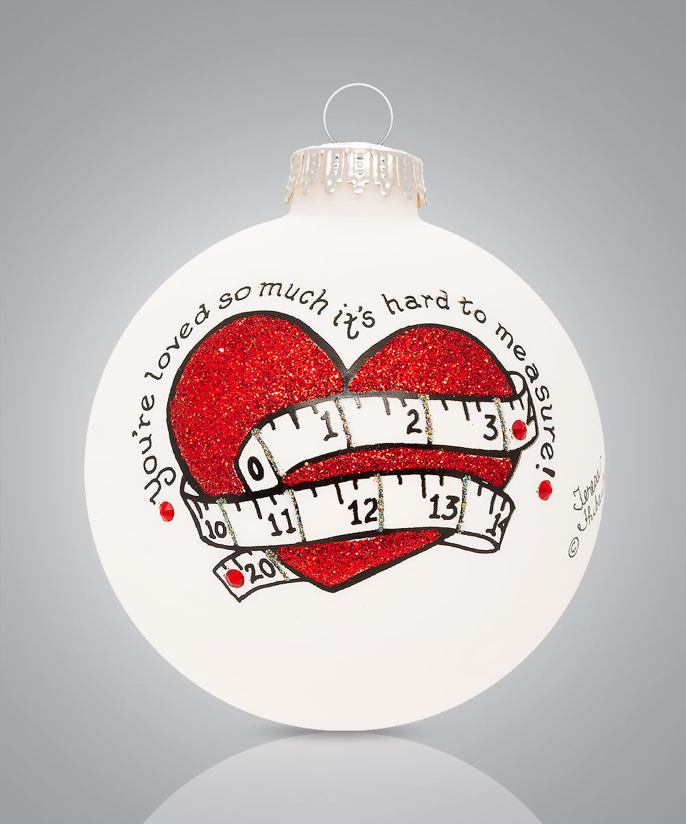 Hand-painted glass ornament with red heart and measuring tape and words “You’re loved so much it’s hard to measure”