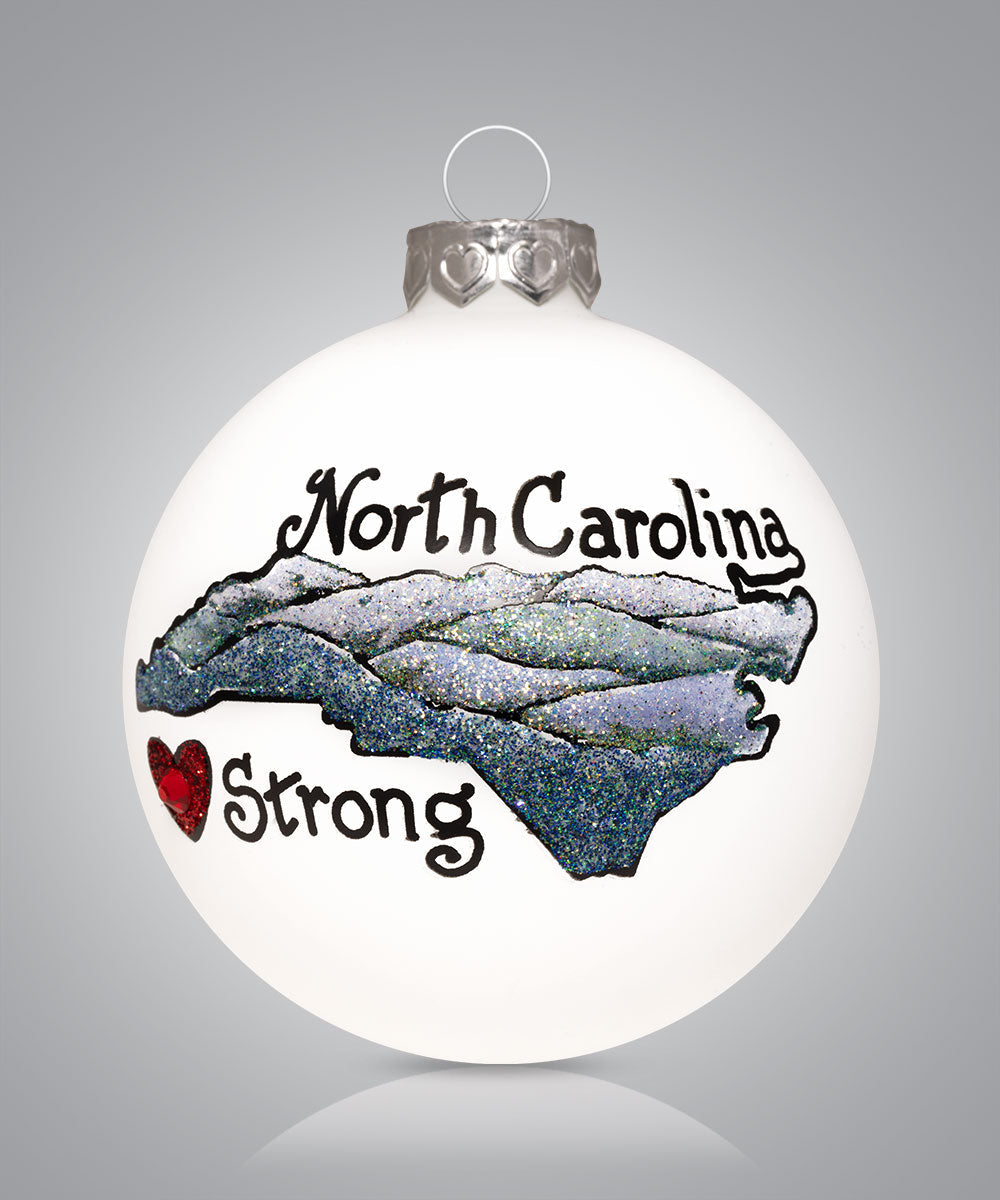 Hand-painted glass ornament with map and mountains saying North Carolina Strong